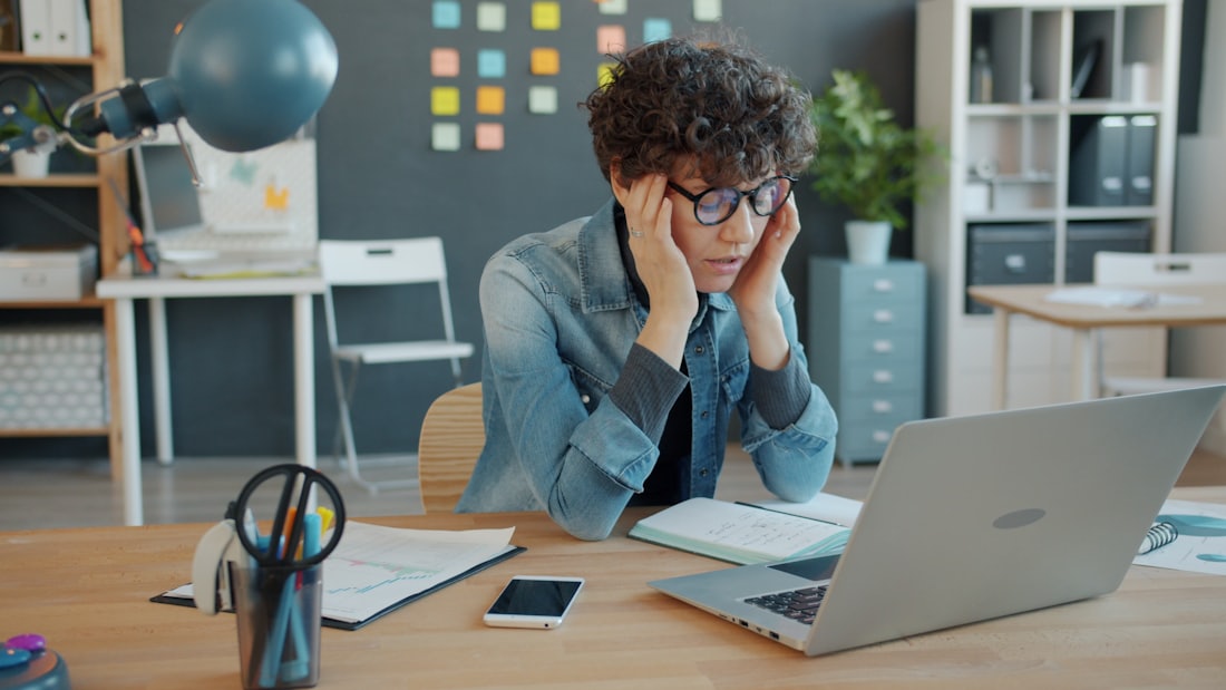 Salariée épuisée, la tête entre les mains à son bureau — situation de mal-être au travail